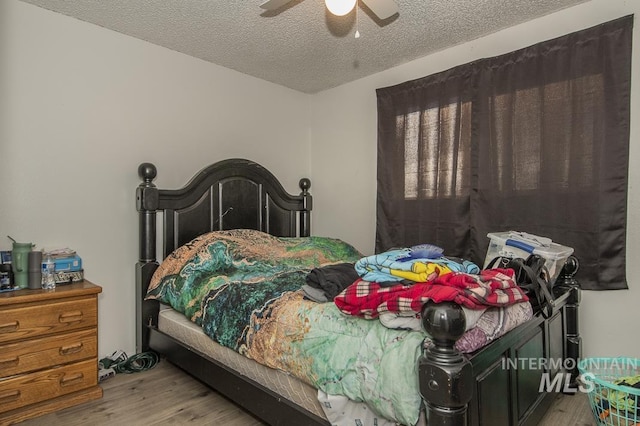 bedroom featuring ceiling fan, a textured ceiling, and light wood-type flooring