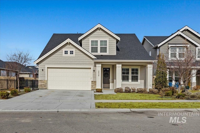 craftsman-style house with a garage, concrete driveway, stone siding, fence, and a front yard