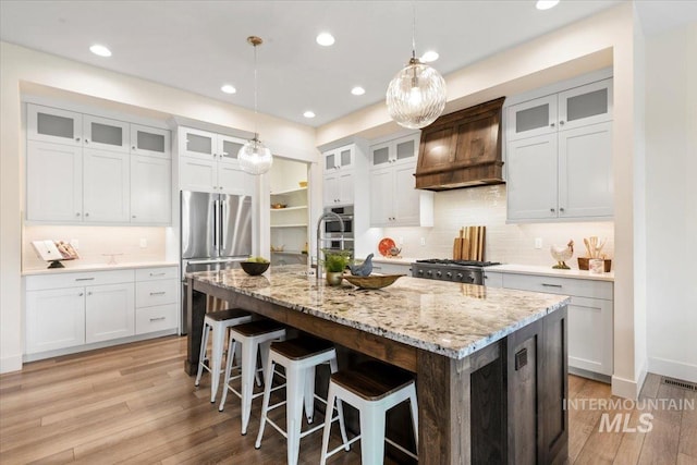 7478 W Palamas, Eagle, ID 83616 - kitchen featuring appliances with stainless steel finishes, custom range hood, light wood-style floors, a kitchen breakfast bar, and recessed lighting