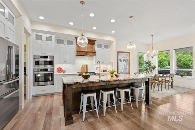 7478 W Palamas, Eagle, ID 83616 - kitchen with appliances with stainless steel finishes, backsplash, light wood finished floors, light stone counters, and a kitchen bar