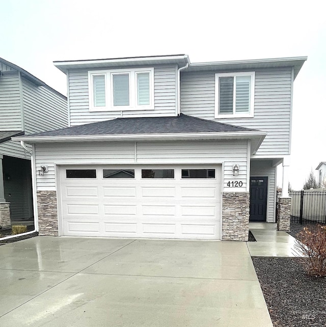 view of front of property featuring a garage, stone siding, fence, and concrete driveway