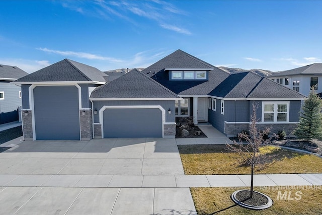 view of front of house featuring a garage, stone siding, a shingled roof, and concrete driveway