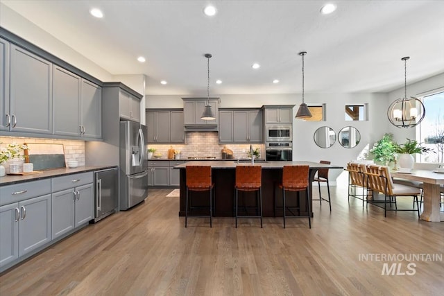 kitchen with wine cooler, a breakfast bar, stainless steel appliances, gray cabinetry, and a sink