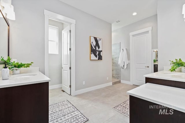 bathroom with two vanities, a sink, baseboards, and a walk in shower