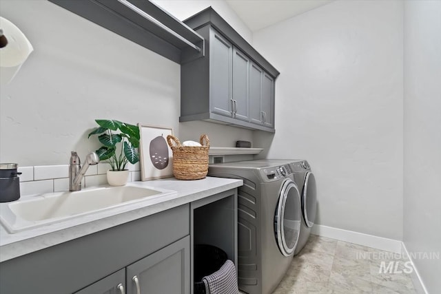 laundry area with washer and clothes dryer, a sink, cabinet space, and baseboards