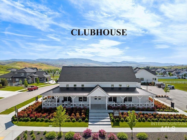 view of front of home featuring metal roof, a residential view, a mountain view, and a porch