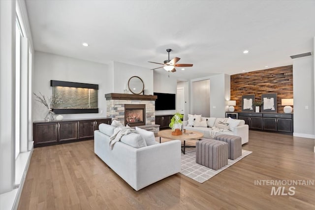 living room featuring a fireplace, light wood-style flooring, and recessed lighting