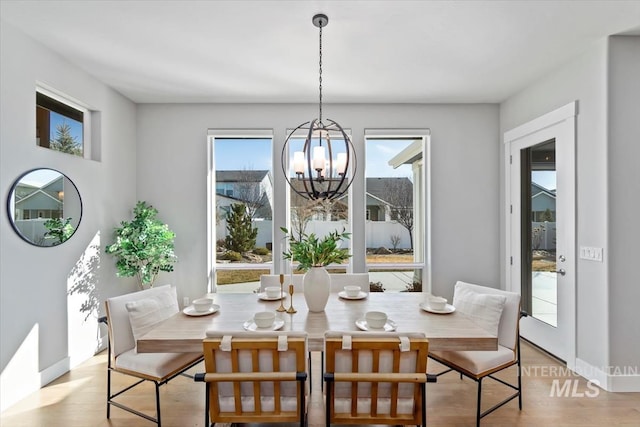 dining area featuring baseboards, light wood finished floors, and an inviting chandelier