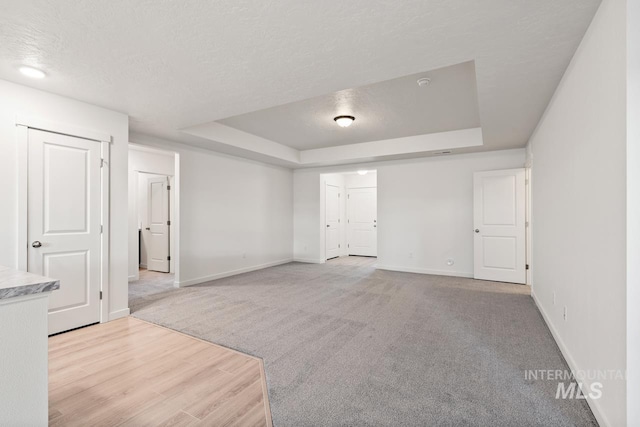 17892 Sunset Ridge Ave, Nampa, ID 83687 - spare room featuring baseboards, light wood-type flooring, light carpet, a textured ceiling, and a raised ceiling
