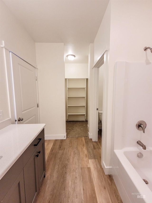 full bathroom featuring toilet, vanity, shower / bathtub combination, and hardwood / wood-style floors