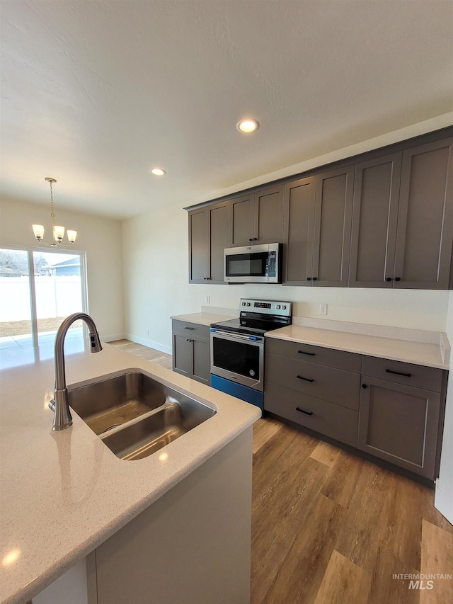 kitchen with stainless steel appliances, hardwood / wood-style flooring, sink, a chandelier, and pendant lighting