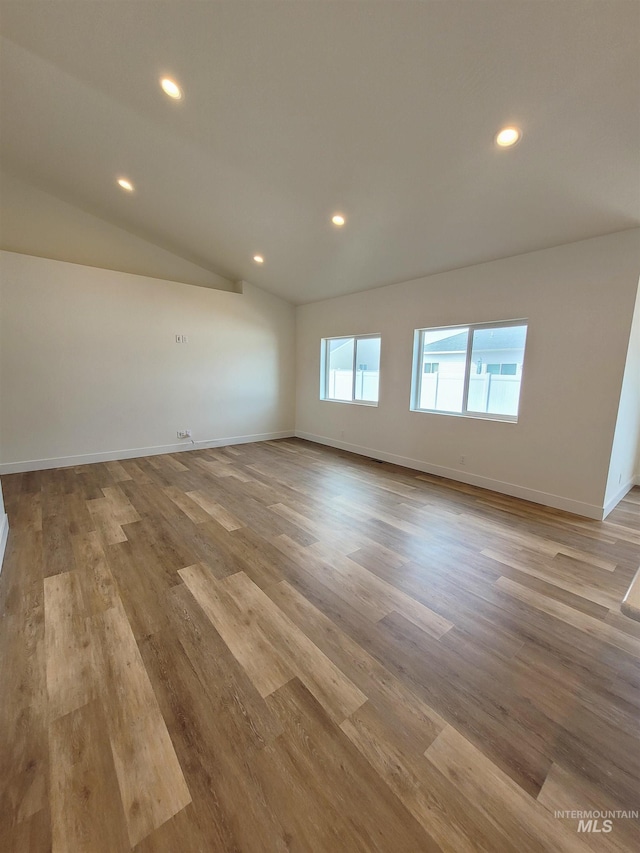 spare room with light wood-type flooring and vaulted ceiling