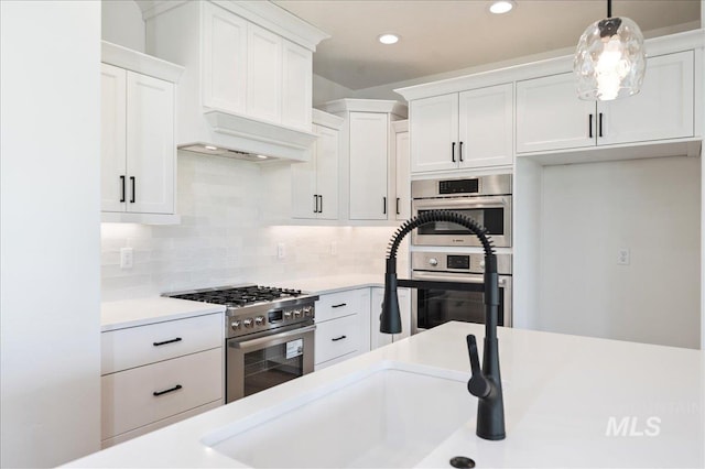 kitchen with light countertops, hanging light fixtures, white cabinets, and stainless steel appliances