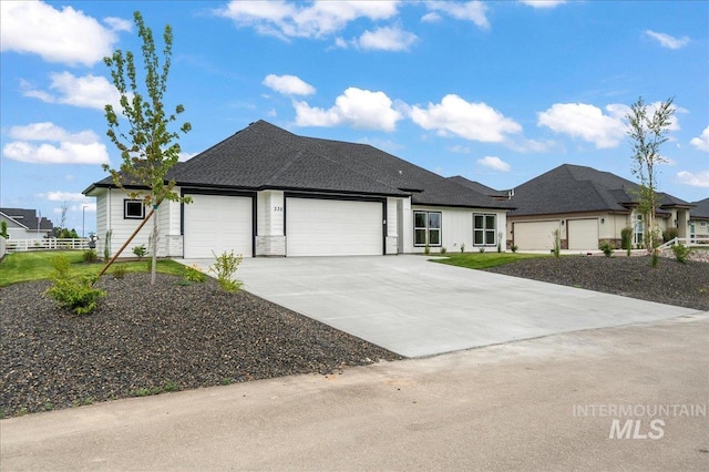 view of front of property with driveway, roof with shingles, an attached garage, and fence