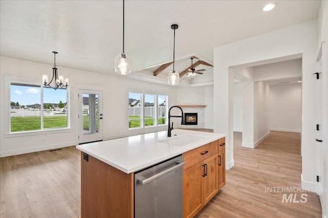 kitchen featuring an island with sink, open floor plan, light countertops, stainless steel dishwasher, and a sink