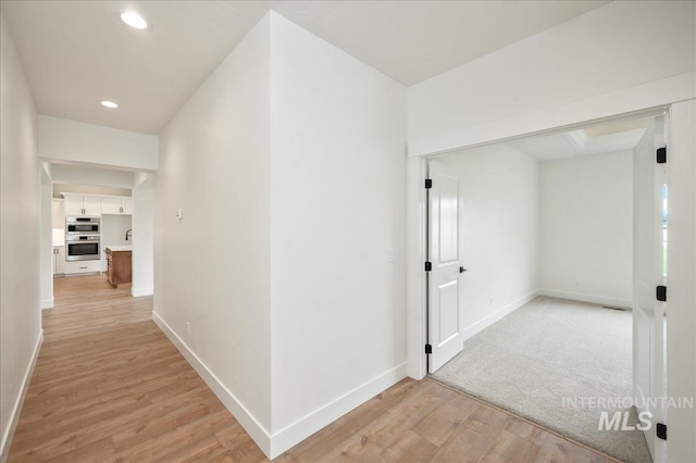 corridor with light wood finished floors, recessed lighting, and baseboards