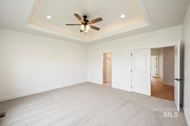 unfurnished bedroom featuring recessed lighting, light carpet, baseboards, ornamental molding, and a raised ceiling