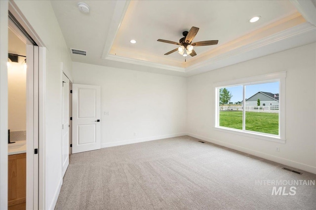 unfurnished bedroom with carpet, a raised ceiling, visible vents, ornamental molding, and baseboards