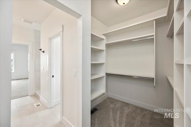 walk in closet featuring light colored carpet and visible vents