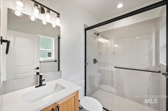 bathroom with toilet, a shower stall, and vanity