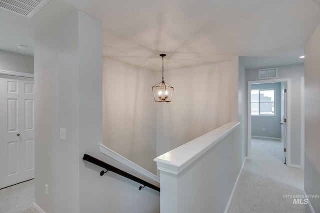 hallway featuring a chandelier and light carpet