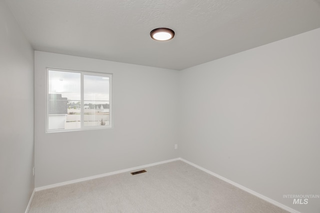 carpeted empty room with a textured ceiling