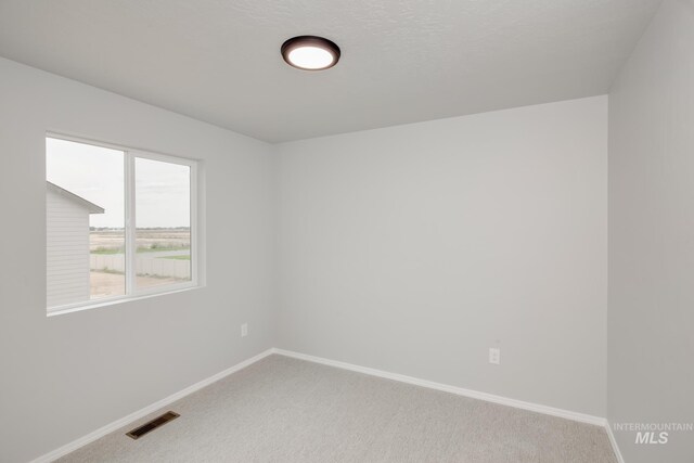 carpeted spare room featuring a textured ceiling