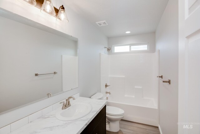 full bathroom featuring washtub / shower combination, wood-type flooring, toilet, and vanity