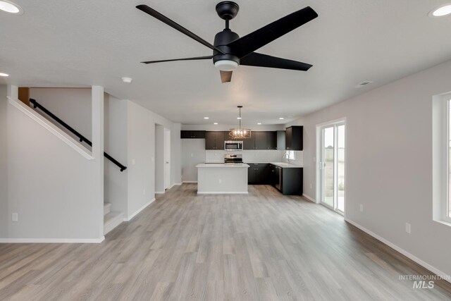 unfurnished living room with ceiling fan with notable chandelier and light hardwood / wood-style floors