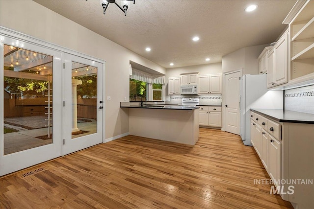 2920 S Givens Way, Meridian, ID 83642 - kitchen with white microwave, stove, a peninsula, light wood-type flooring, and white cabinetry