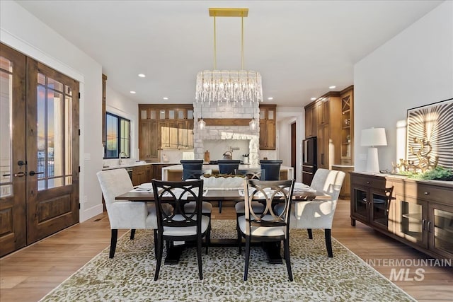 dining area featuring french doors, recessed lighting, light wood-style flooring, and a fireplace