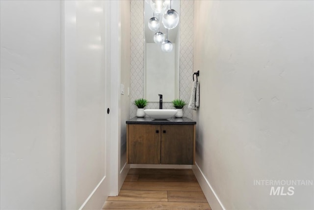 bathroom with baseboards, wood finished floors, and vanity