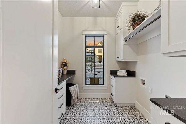 washroom featuring baseboards, washer hookup, cabinet space, and light floors