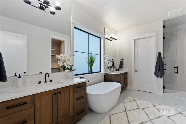 bathroom featuring a freestanding bath, a stall shower, two vanities, a sink, and marble finish floor