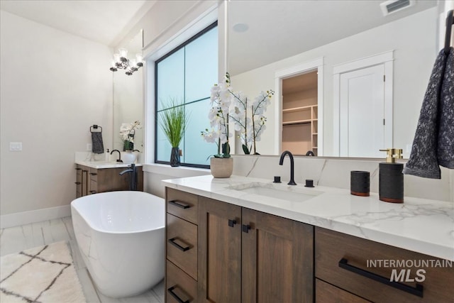 full bath featuring visible vents, vanity, marble finish floor, baseboards, and a soaking tub