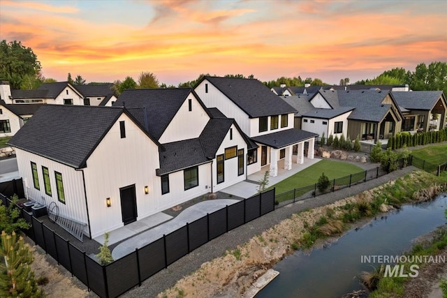 aerial view at dusk featuring a residential view and a water view
