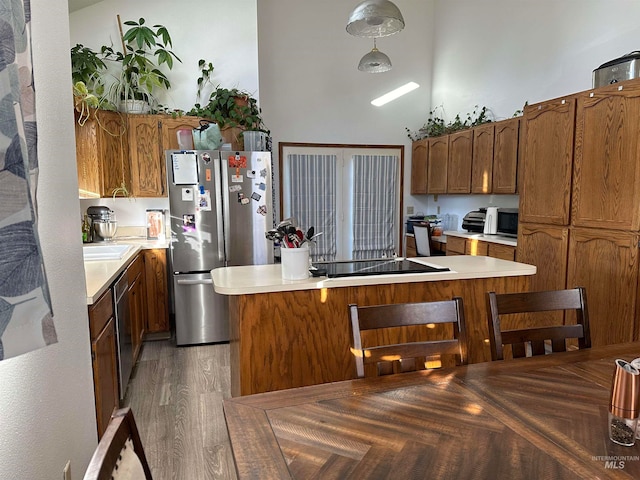 kitchen featuring a high ceiling, hanging light fixtures, hardwood / wood-style flooring, and stainless steel appliances