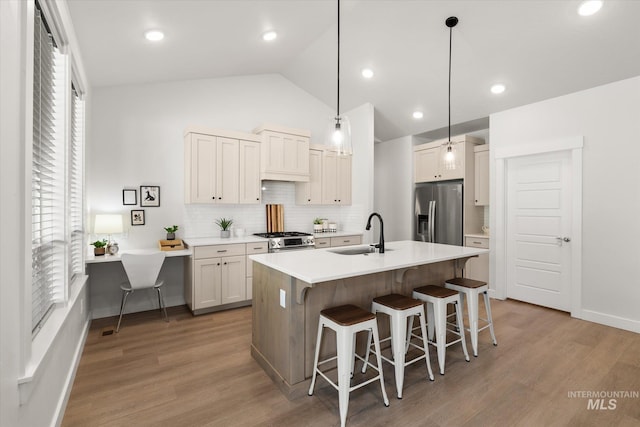 1866 W Windswept Dr, Meridian, ID 83646 - kitchen featuring appliances with stainless steel finishes, decorative backsplash, a kitchen bar, lofted ceiling, and light wood-style flooring