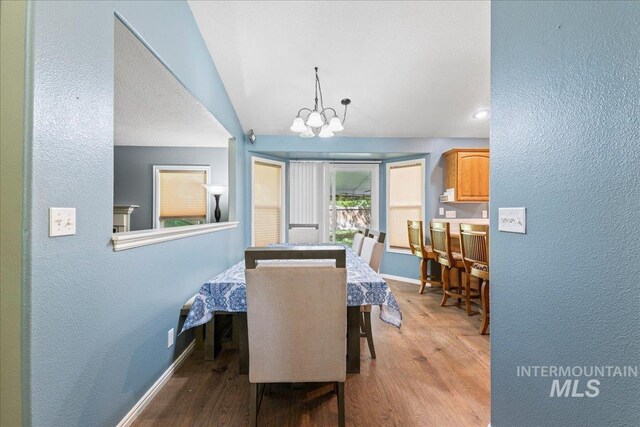 dining room featuring baseboards, wood finished floors, a textured wall, and a chandelier