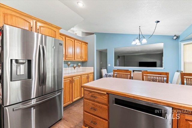 kitchen featuring stainless steel appliances, lofted ceiling, light countertops, light wood-style flooring, and a chandelier