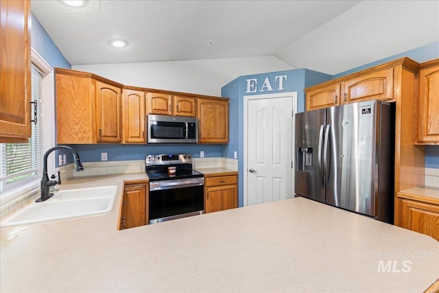 kitchen featuring stainless steel appliances, a sink, lofted ceiling, light countertops, and brown cabinets