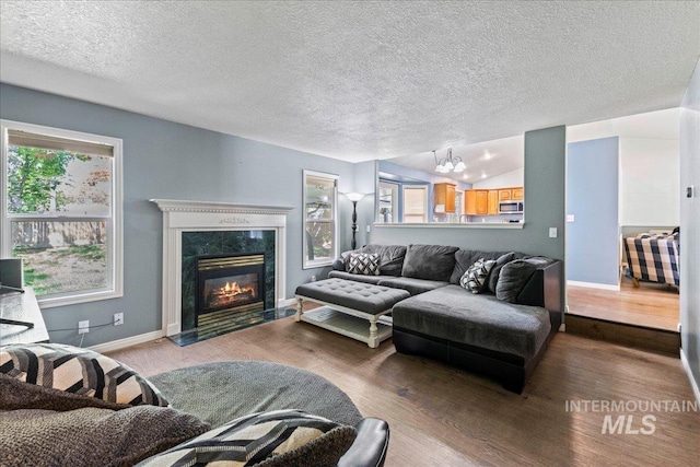 living room with plenty of natural light, wood finished floors, a textured ceiling, and lofted ceiling
