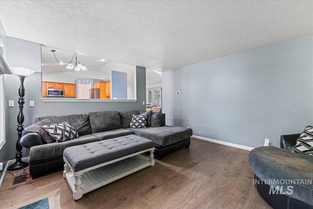 living room featuring wood finished floors, baseboards, a textured ceiling, and lofted ceiling