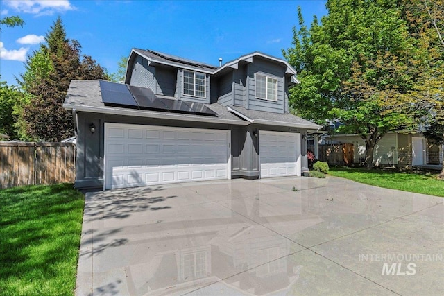 traditional-style home with solar panels, an attached garage, concrete driveway, and a shingled roof