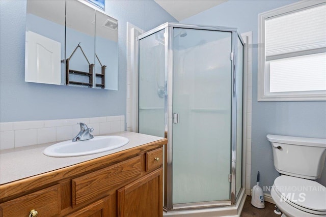 full bathroom with a stall shower, toilet, and vanity