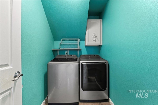 laundry area featuring washer and dryer, baseboards, cabinet space, and a textured wall