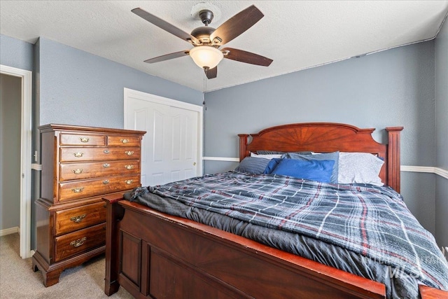 bedroom featuring light colored carpet, ceiling fan, baseboards, and a closet