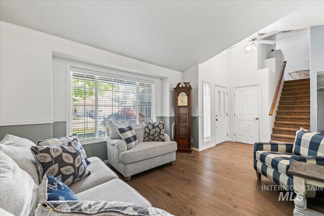 living area featuring wood finished floors, stairs, ceiling fan, high vaulted ceiling, and baseboards