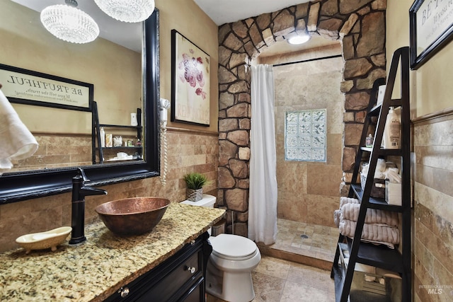 bathroom with walk in shower, toilet, tile walls, vanity, and tile patterned flooring