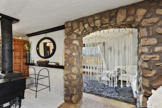 unfurnished dining area with light tile patterned flooring, a textured ceiling, and a wood stove